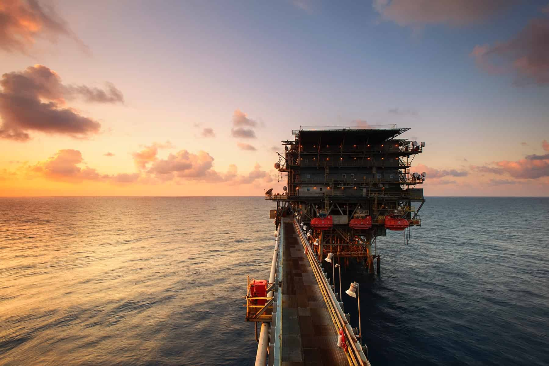 oil and gas rig out in the ocean during sunset