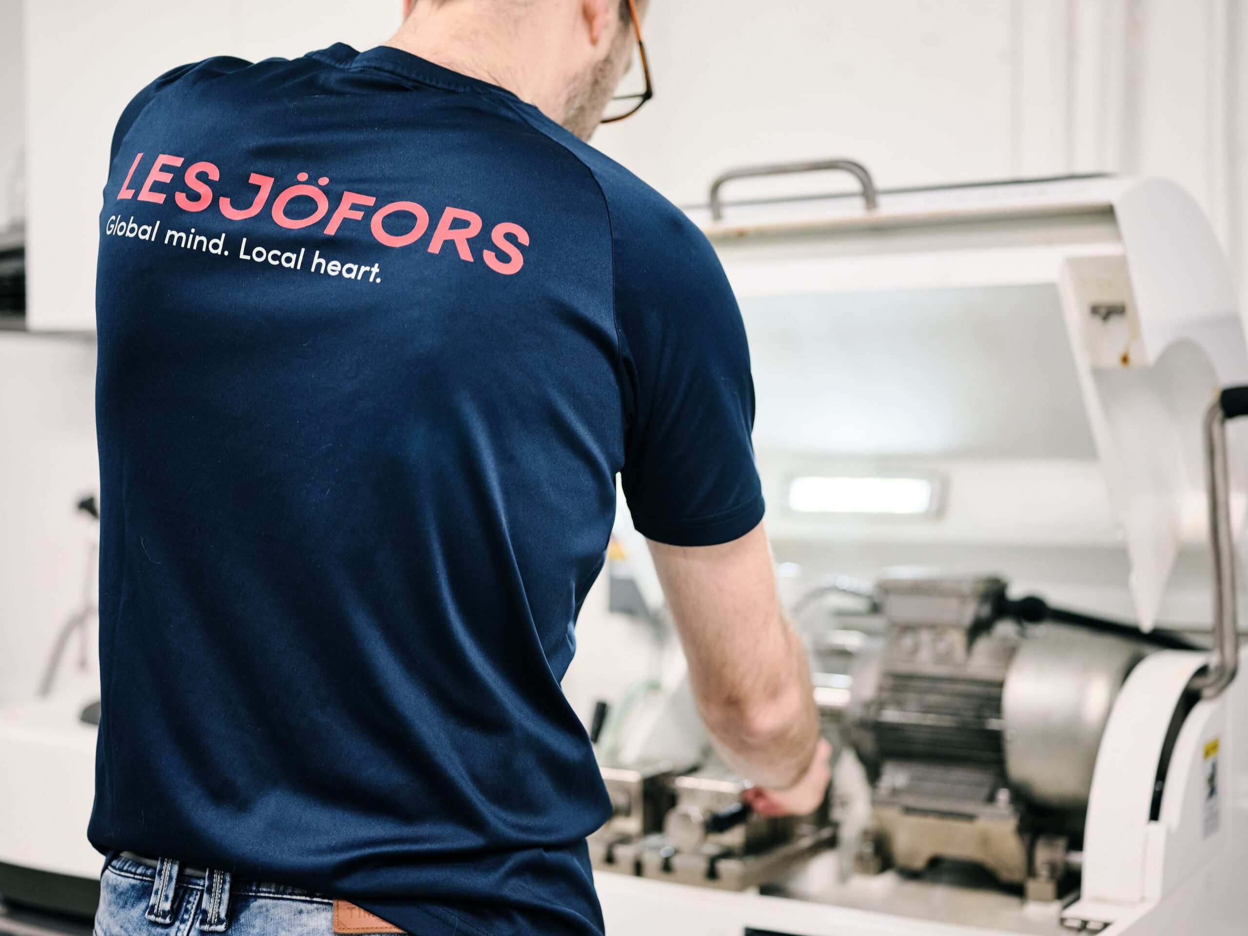 A Lesjöfors engineer preparing a coil spring sample for precision testing using specialized spring testing equipment.